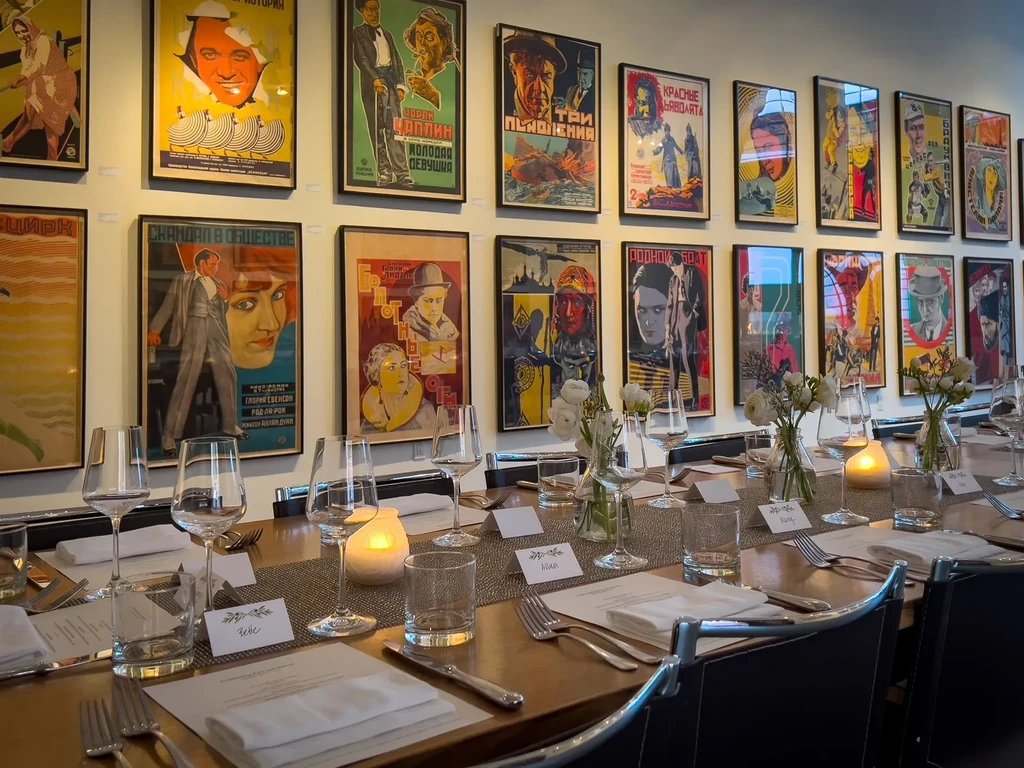 Long table set for dinner with vintage movie posters on the wall.