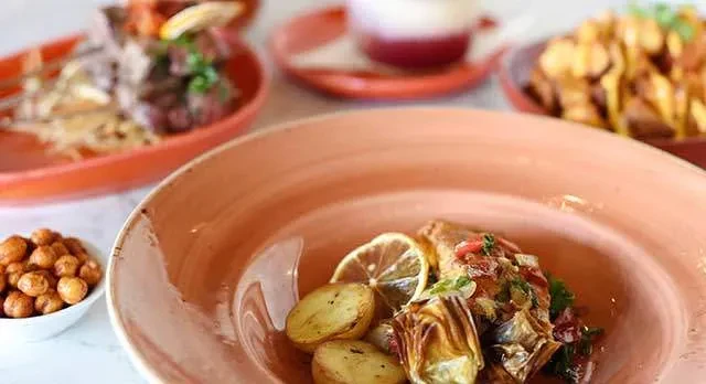 Four plates of food including a fish dish with potatoes and artichokes.