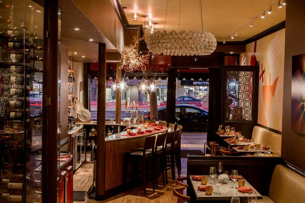 A dimly lit restaurant interior with a bar, wine rack, and dining tables.