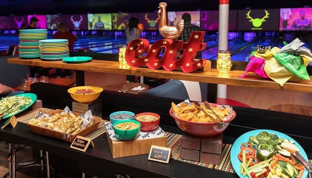 Food buffet at a bowling alley with "eat" sign and colorful plates.