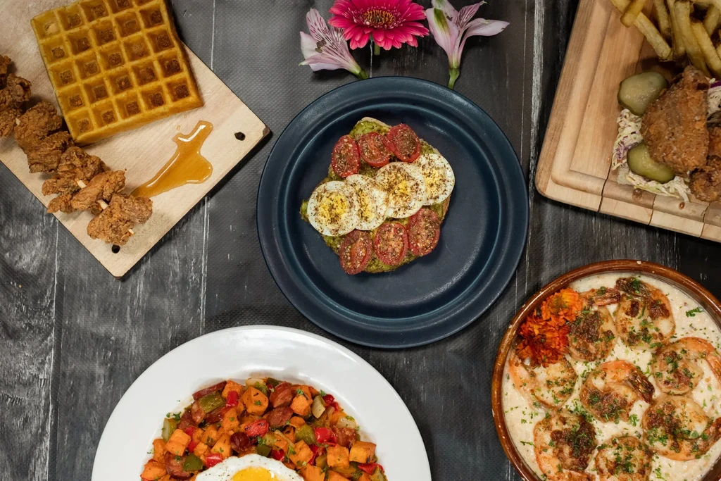 Overhead view of several breakfast and brunch dishes on a dark table.