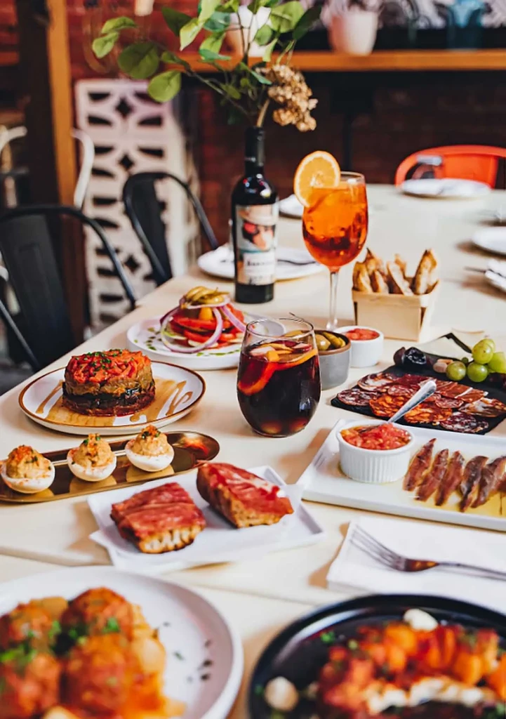 A table filled with a spread of Spanish tapas and drinks.