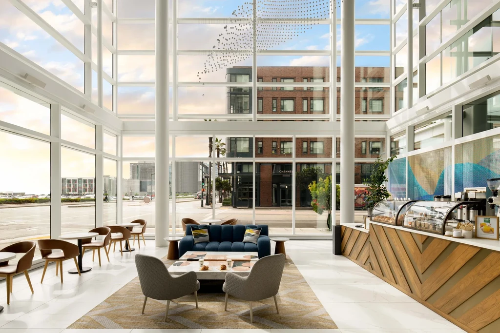 A modern lobby with a coffee bar, seating, and large windows overlooking a city street.