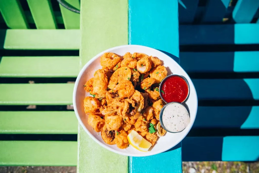 Fried calamari with red and white sauces on a colorful table.
