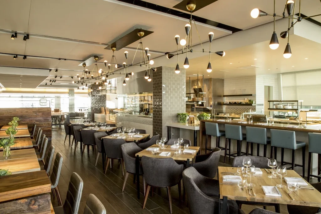 An upscale modern restaurant with dining tables, chairs, and an open kitchen.