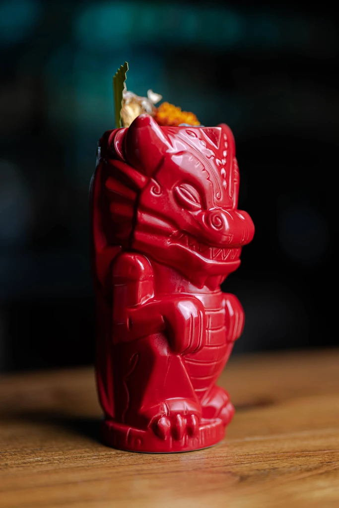 A bright red, dragon-shaped Tiki mug with garnish.