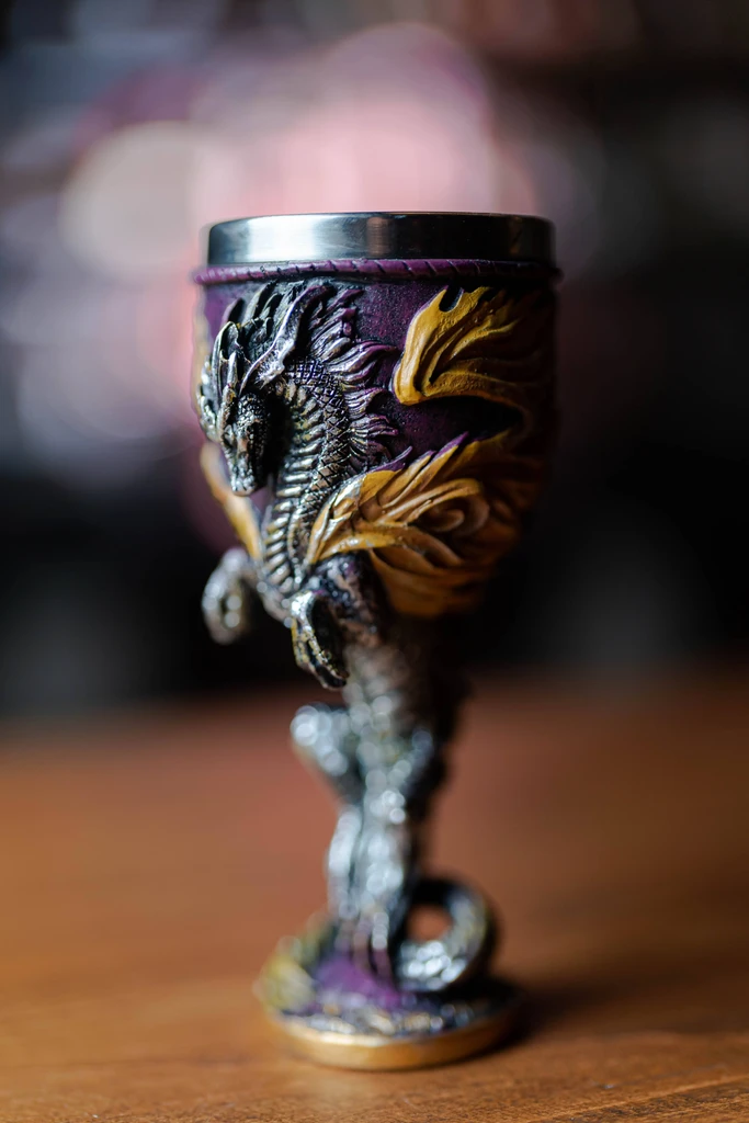 A dragon-themed goblet with a purple and gold body on a wooden surface.