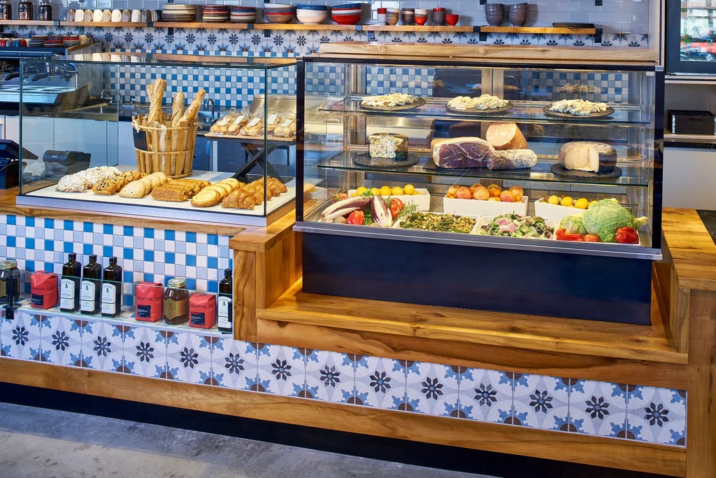 Deli counter with baked goods, meats, cheeses, and salads on display.
