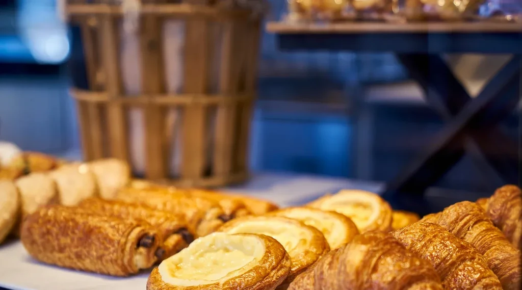 An array of pastries including croissants and danishes on a white tray.
