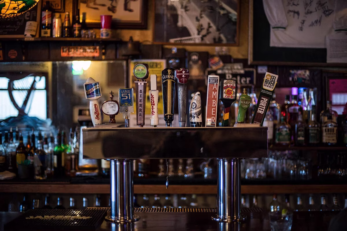 Close-up of multiple beer tap handles at a bar.