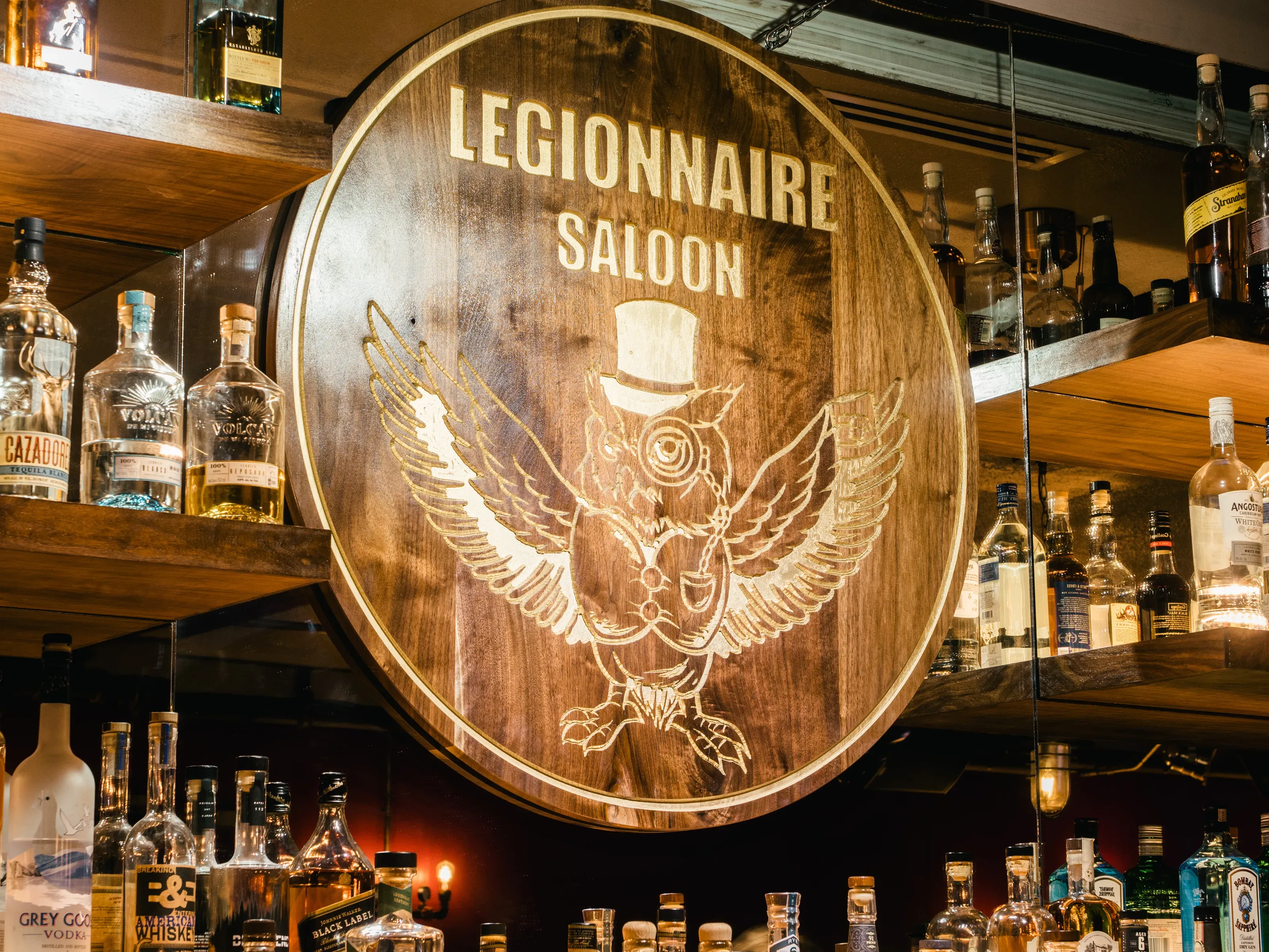 Round wooden sign for Legionnaire Saloon with a top-hatted owl.