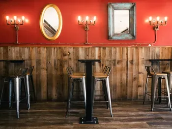 Bar interior with red walls, wood paneling, mirrors, and stools.