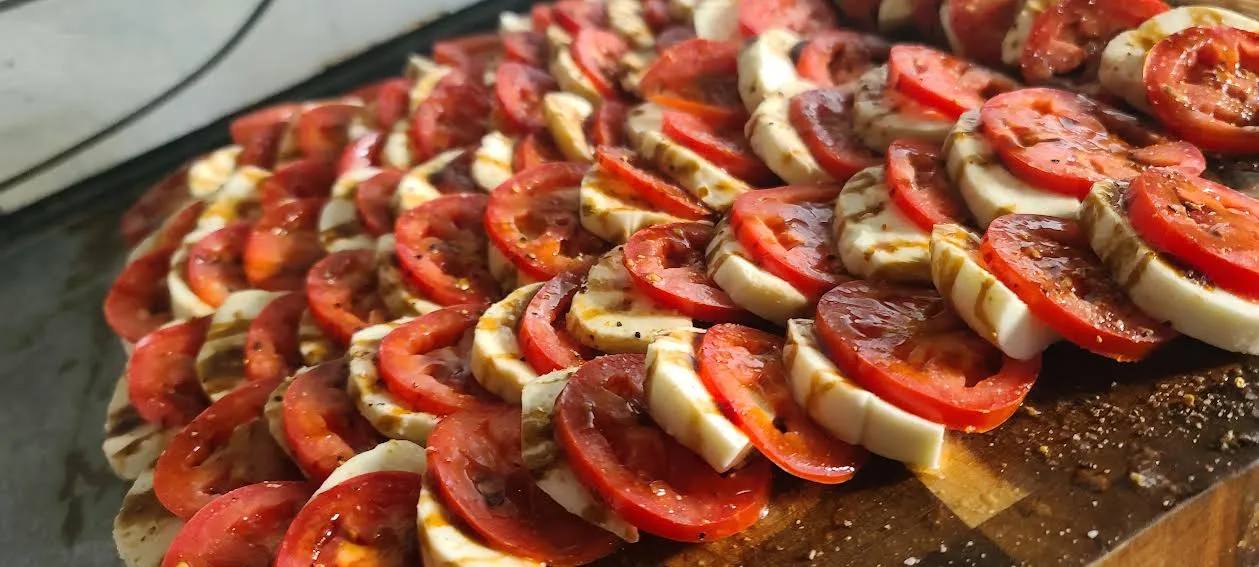 Caprese salad with grilled mozzarella, tomatoes, balsamic glaze, and seasoning.