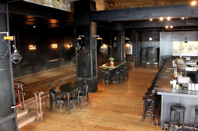Dark, industrial interior with shuffleboard court, bar, and wooden floor.
