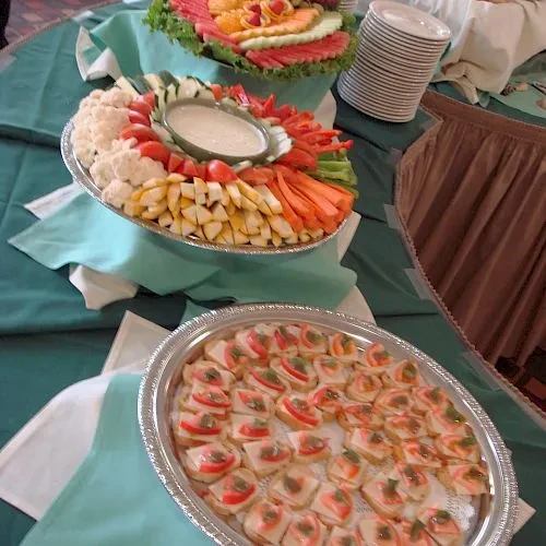 A buffet table with fruit, vegetable, and canapé platters.