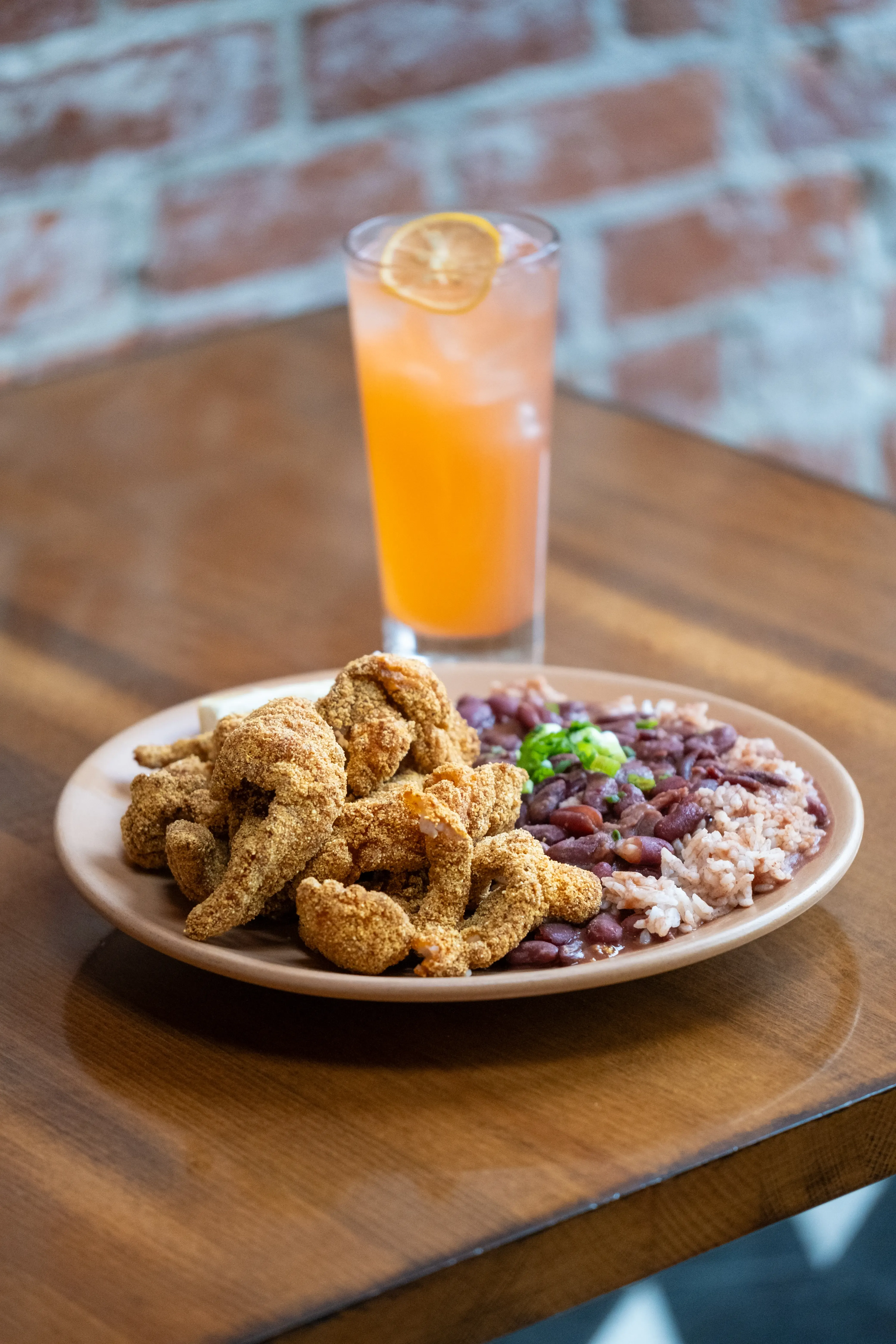 Fried shrimp, red beans, rice, and a tall drink with lemon.