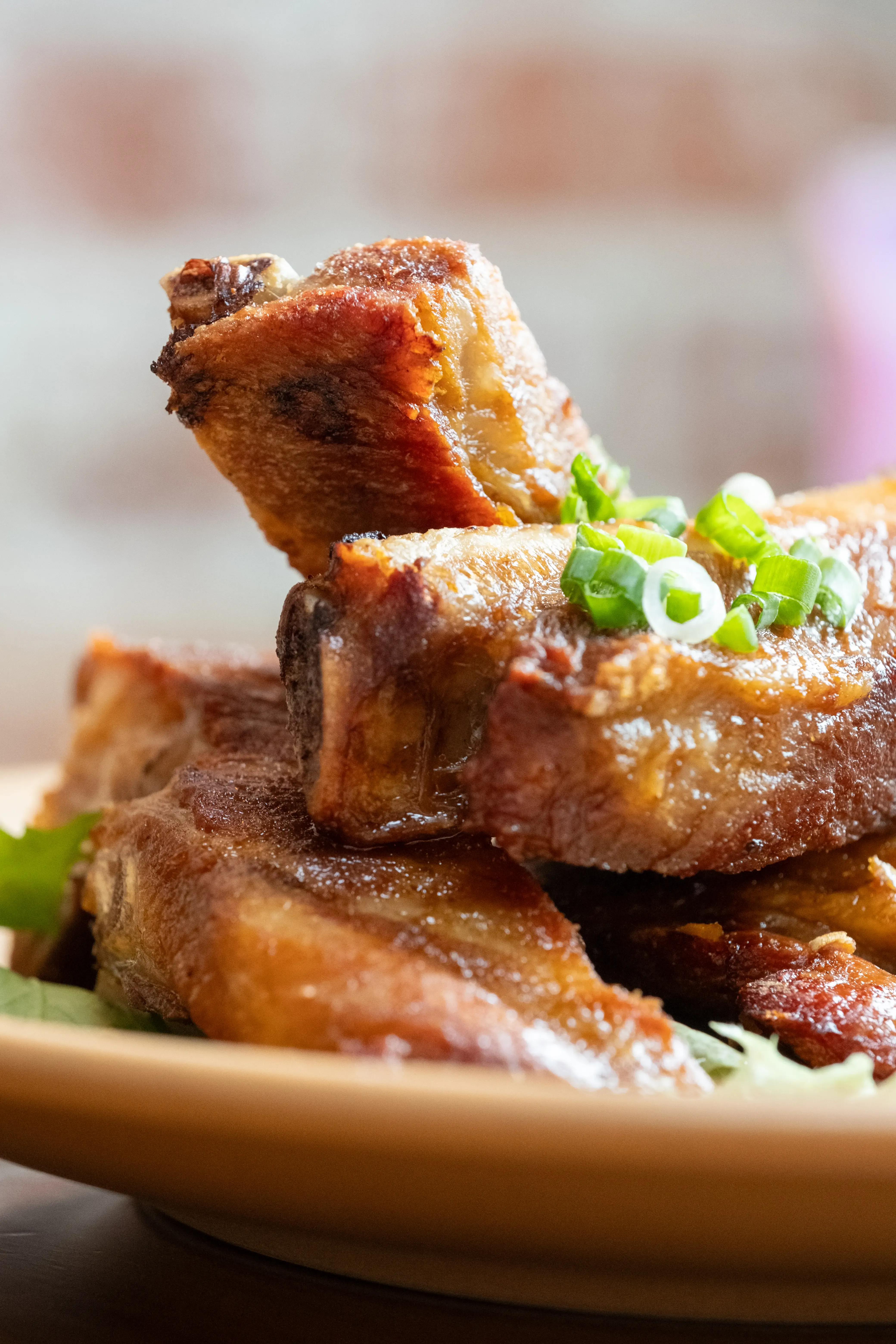 Close-up of glazed meat pieces topped with sliced green onions.