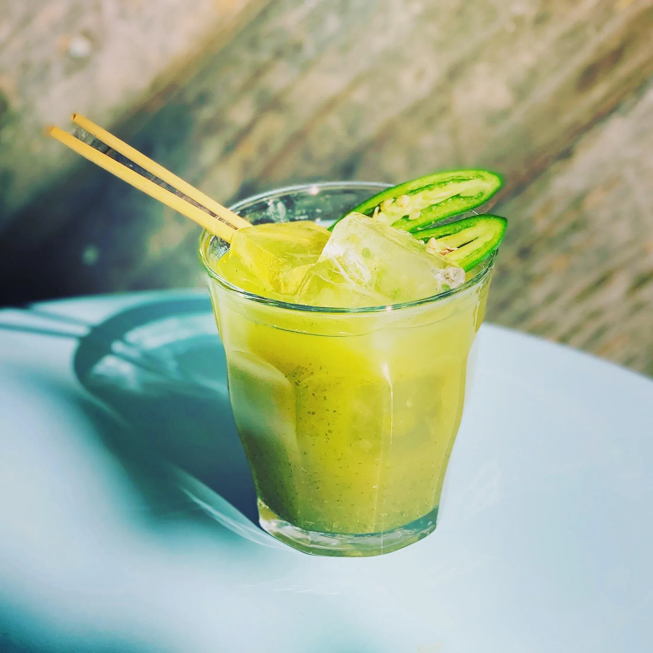 Light green drink with ice, sliced peppers, and yellow sticks.