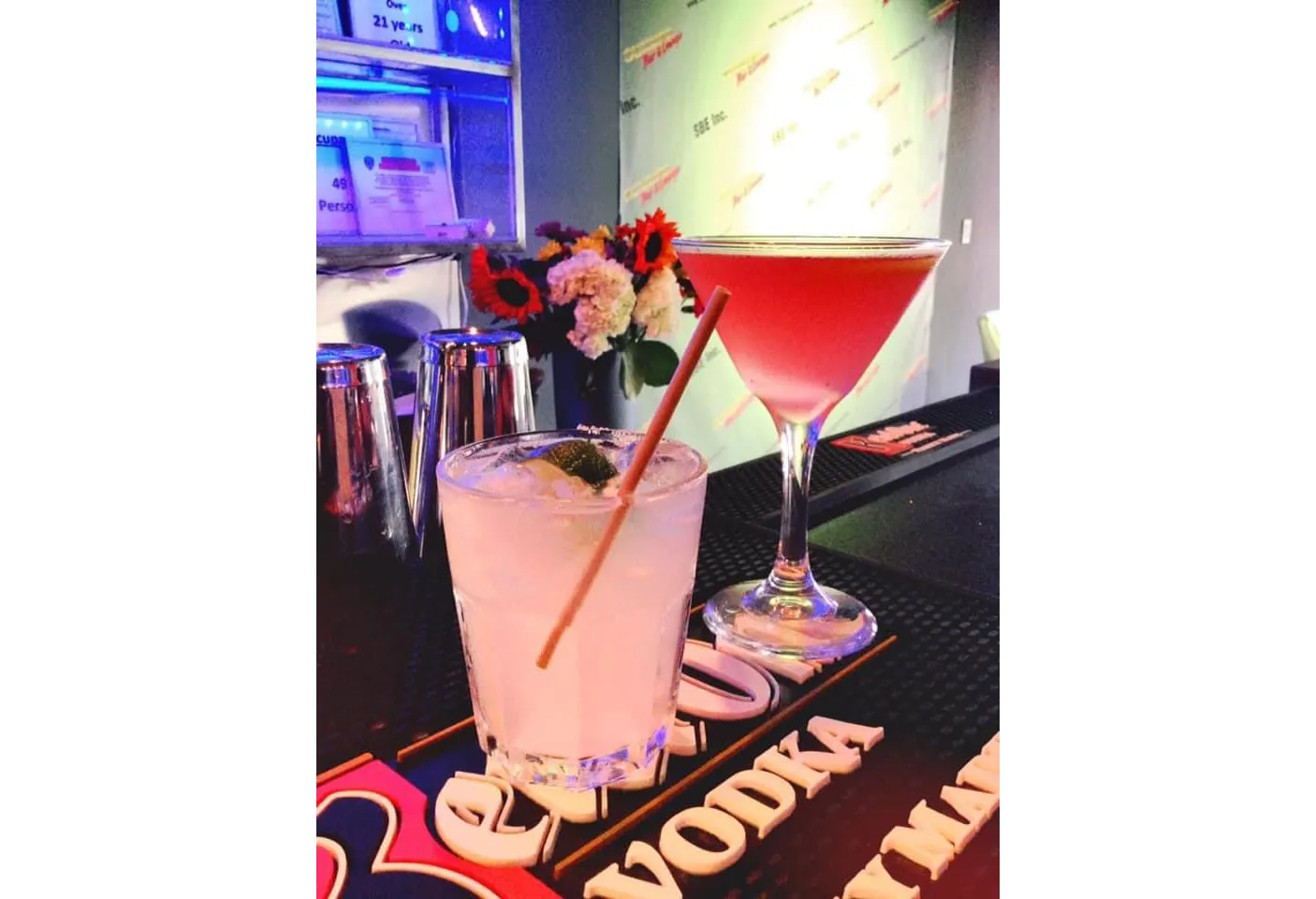 Pink martini and a lime cocktail on a bar counter.
