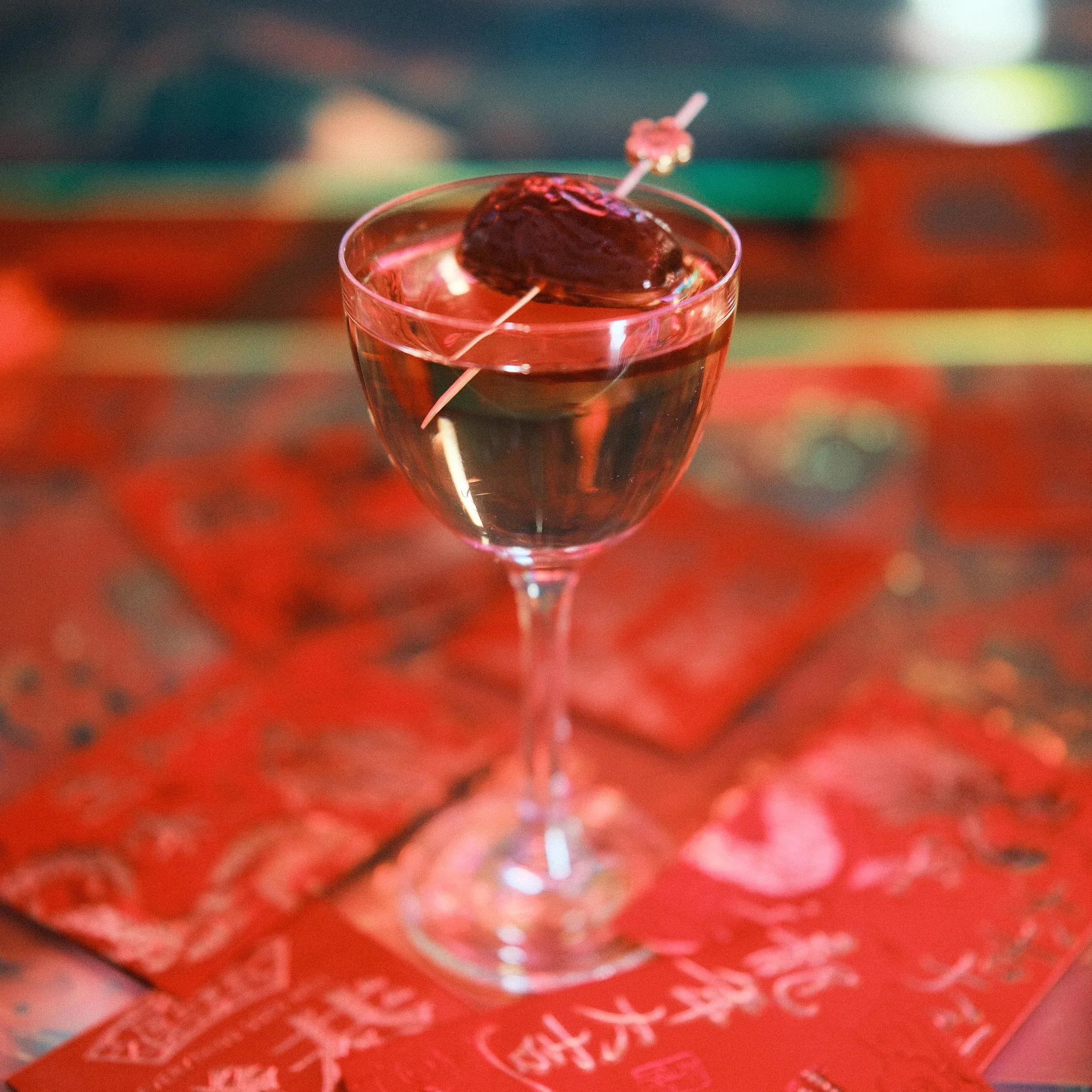 Cocktail garnished with a date, on red envelopes with Chinese characters.