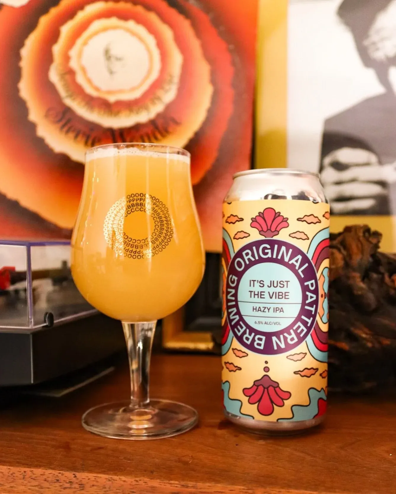 Glass of hazy IPA next to a brightly labeled beer can.