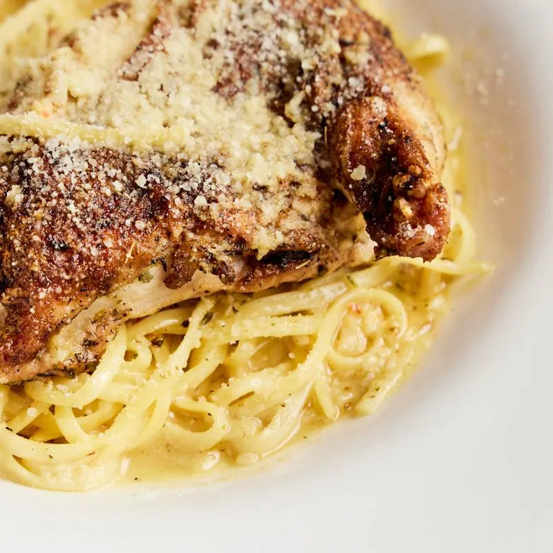 Chicken with grated cheese on creamy pasta.