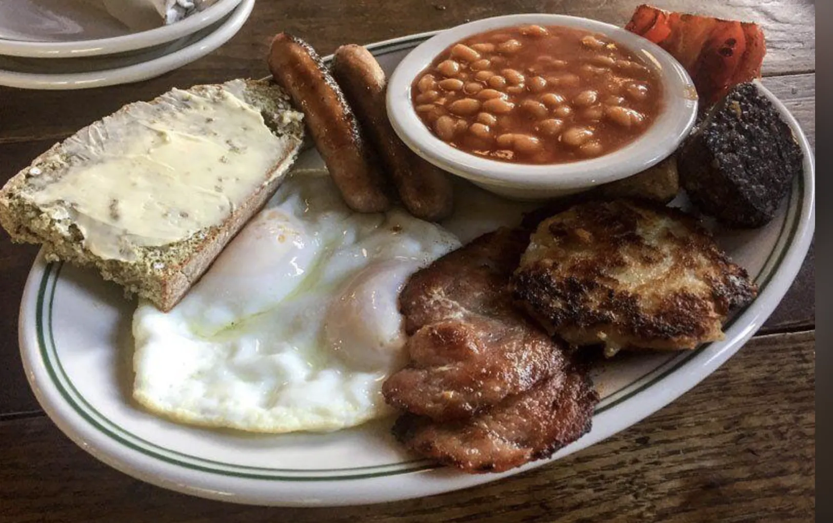A full breakfast with fried eggs, sausages, bacon, beans, and black pudding.