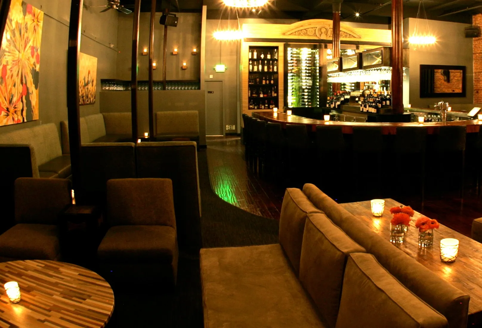 Dimly lit bar and lounge with various seating and a wine wall.