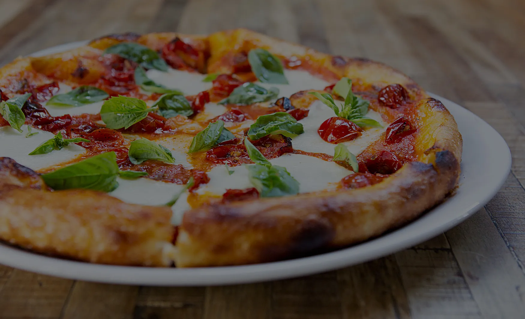 Pizza with melted mozzarella, red tomatoes, and fresh basil leaves.