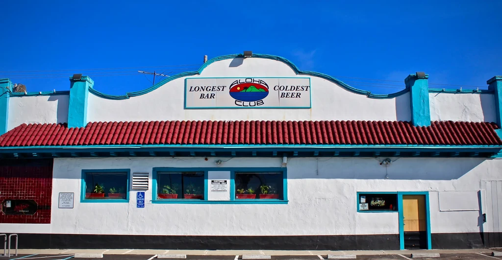 The Aloha Club building with red roof tiles and a bright blue sky.