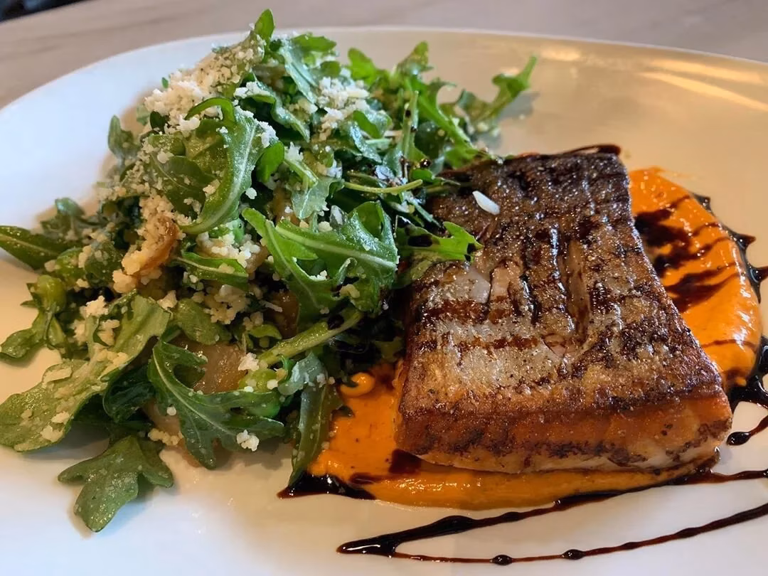 Seared fish, arugula salad with cheese, orange puree, and dark glaze.