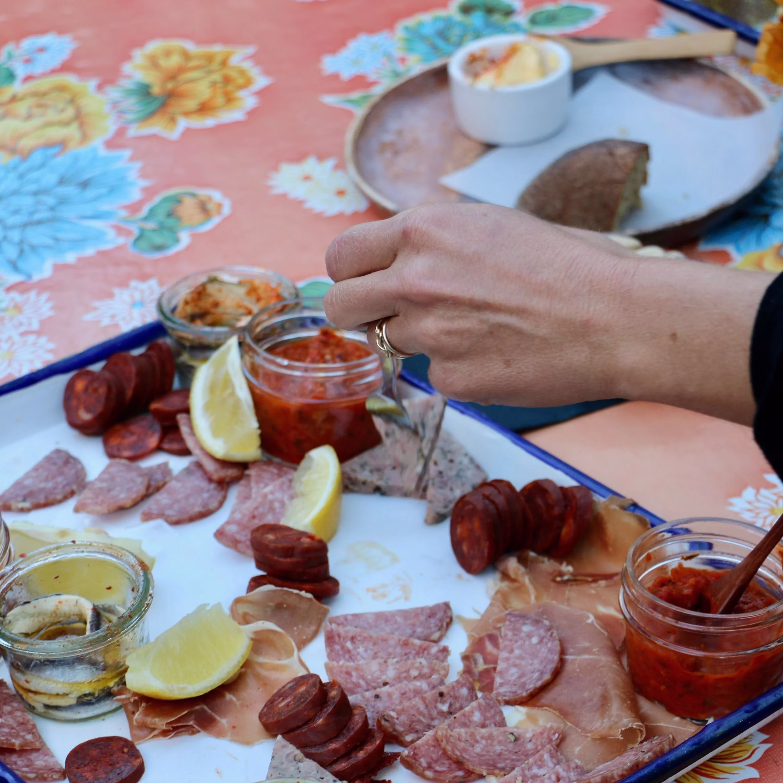 Hand selecting food from a charcuterie and antipasto platter.