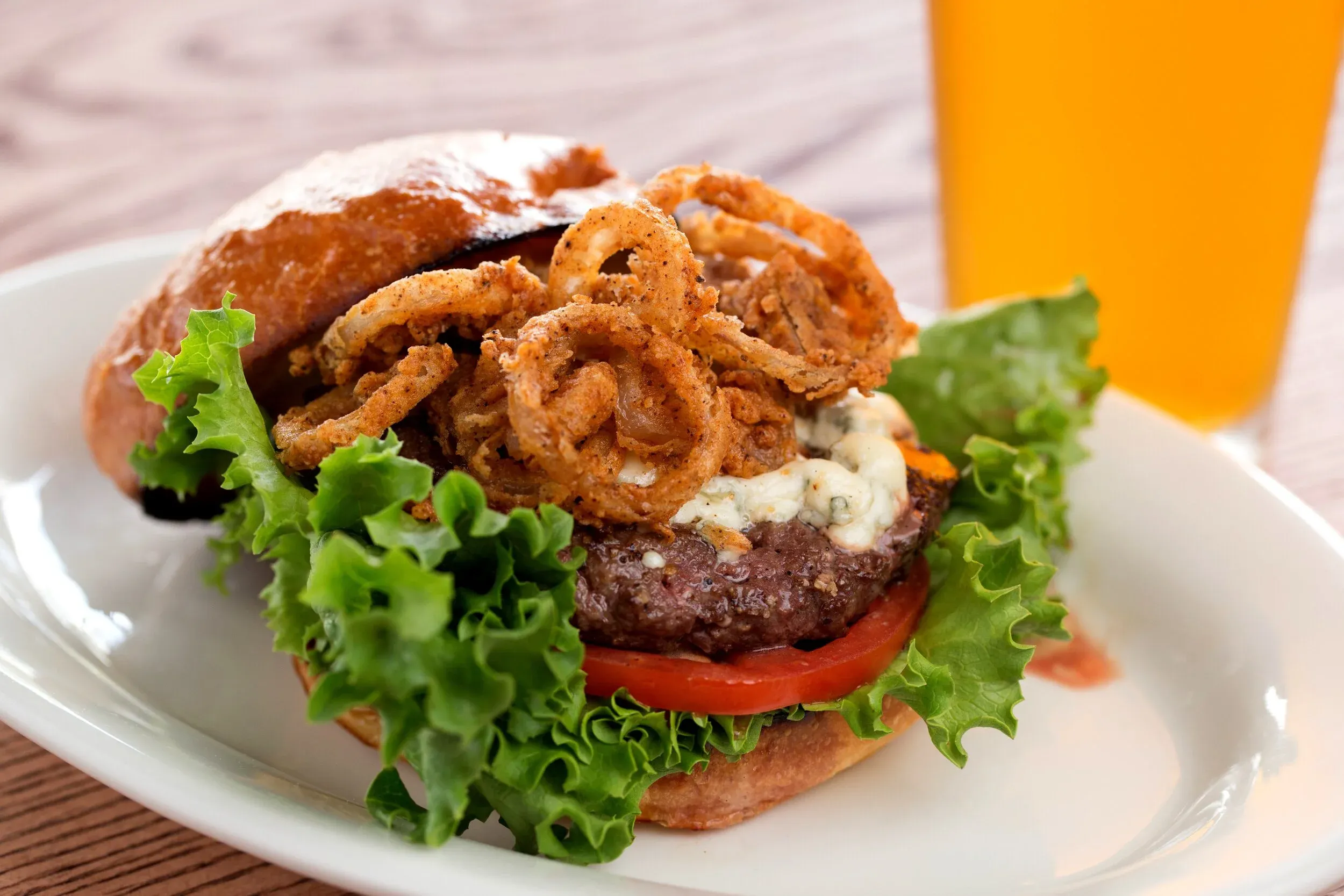 Hamburger with onion rings, blue cheese, lettuce, and tomato.