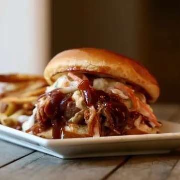 Pulled pork sandwich with coleslaw, barbecue sauce, and a side of fries.