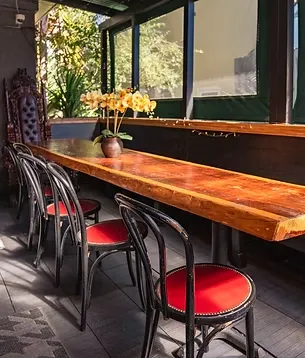 Long wooden table with black chairs, red seats, and yellow orchids.