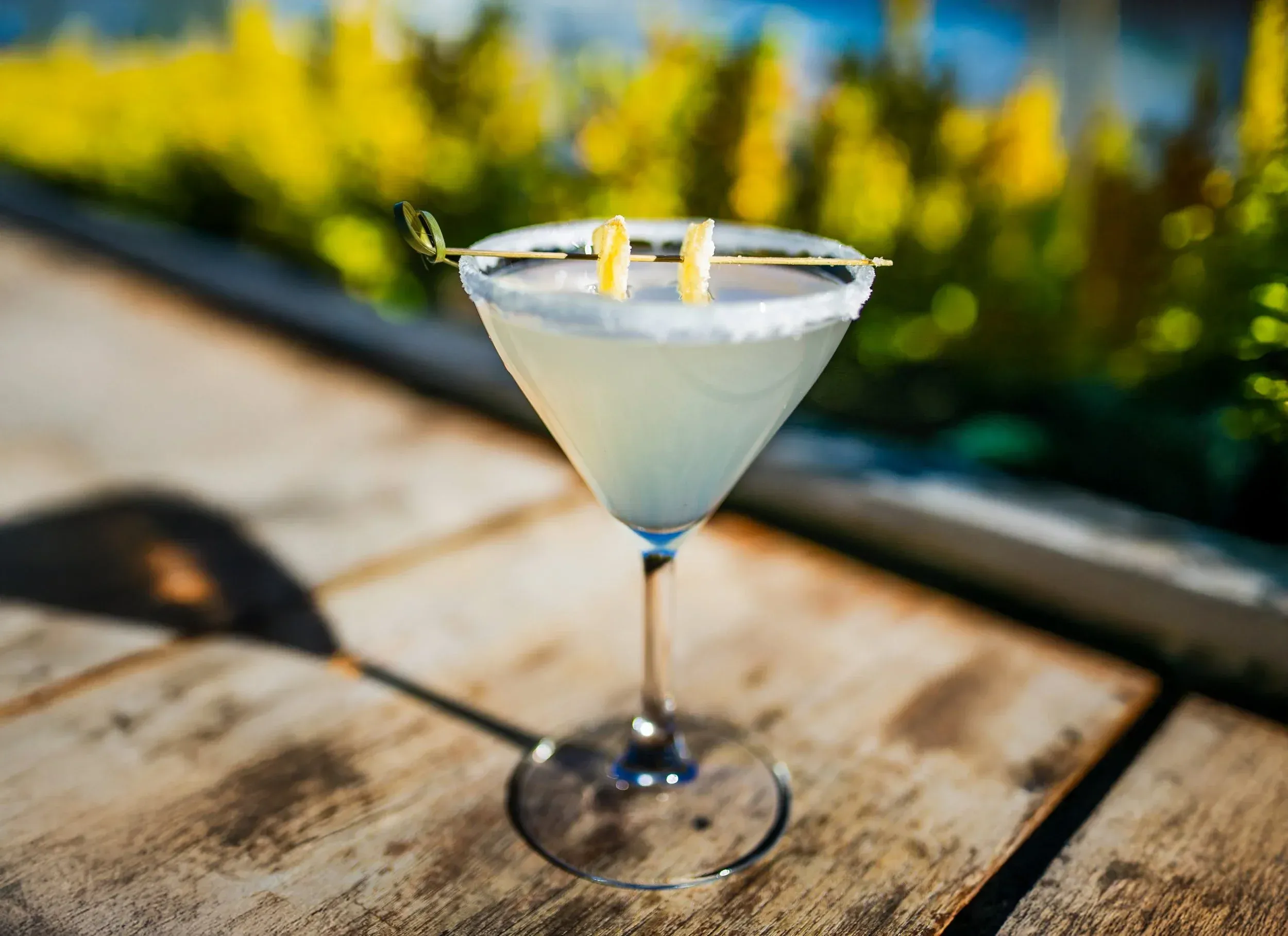 Martini glass with sugared rim and lemon garnish on wooden surface.