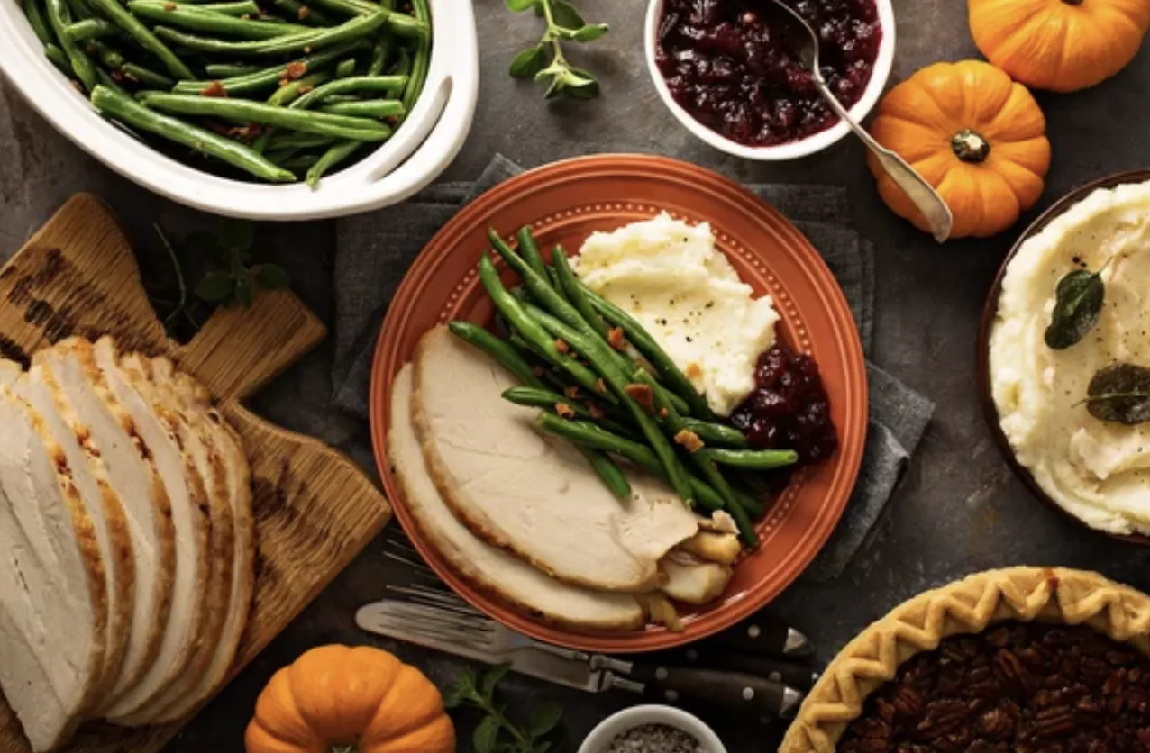 Thanksgiving dinner with turkey, mashed potatoes, green beans, cranberries, and pie.