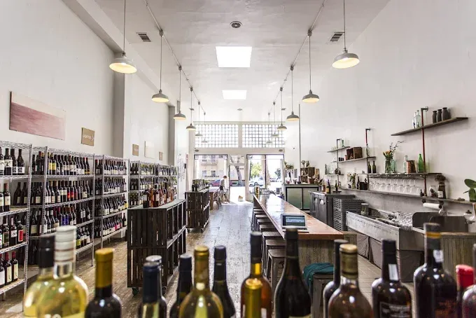Bright liquor store interior with shelves of bottles and a long bar.