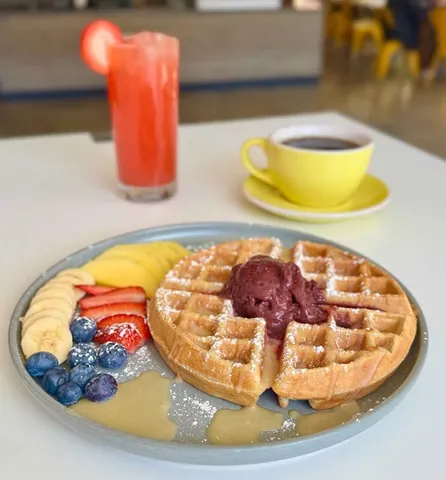 Waffle with fresh fruit, berry sorbet, coffee, and strawberry drink.