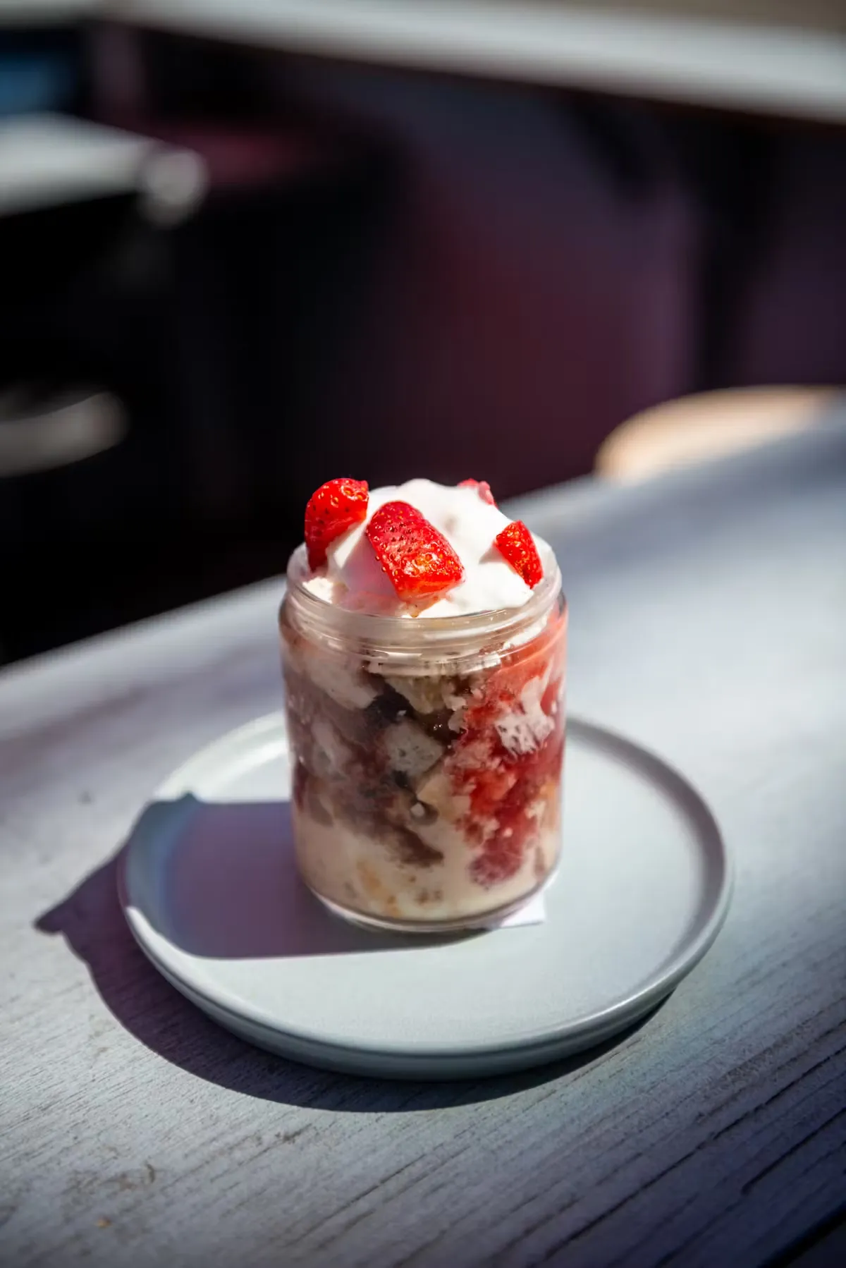 Dessert in a glass jar topped with cream and strawberries.