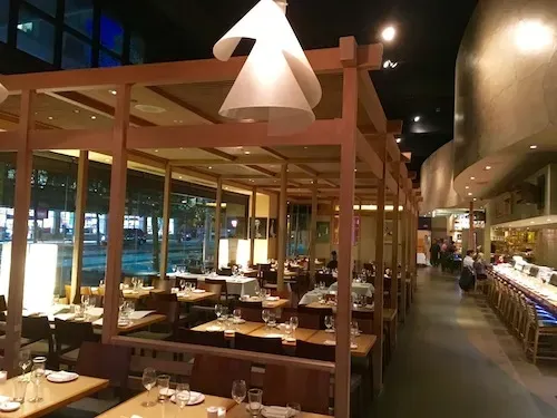 Restaurant interior with wooden framework, dining tables, and a sushi bar.