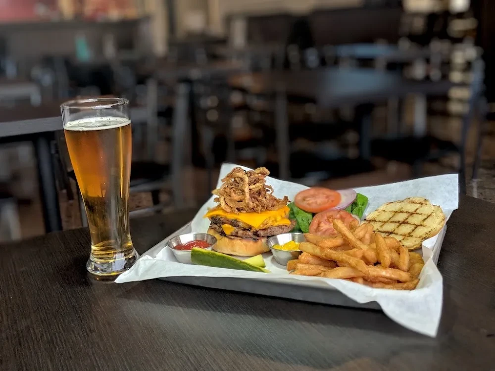 A beer, double cheeseburger, fries, and salad served on a tray.