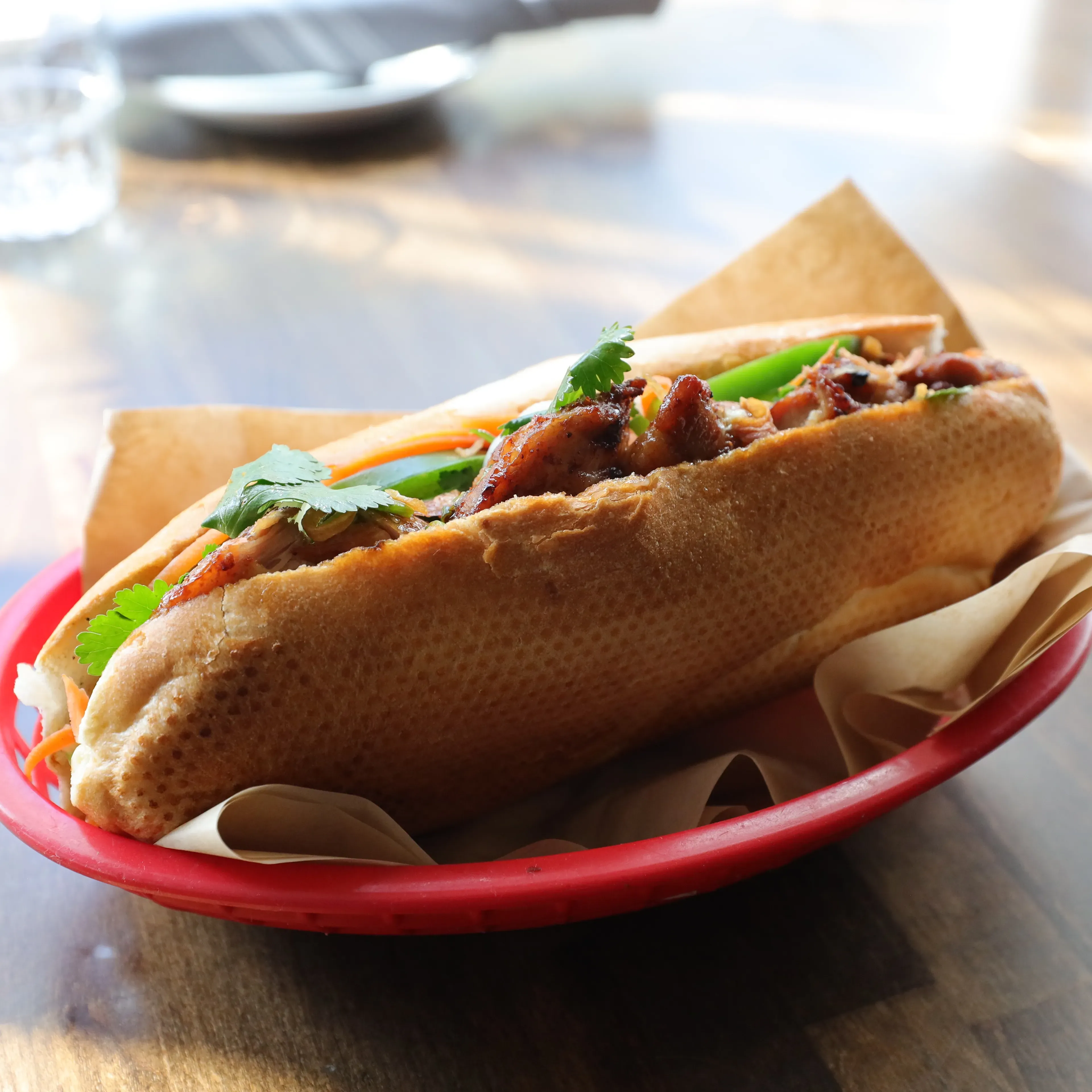 Banh Mi sandwich with grilled meat, cilantro, and pickled vegetables.