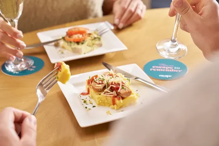 People eating small plates of food and drinking at a table.