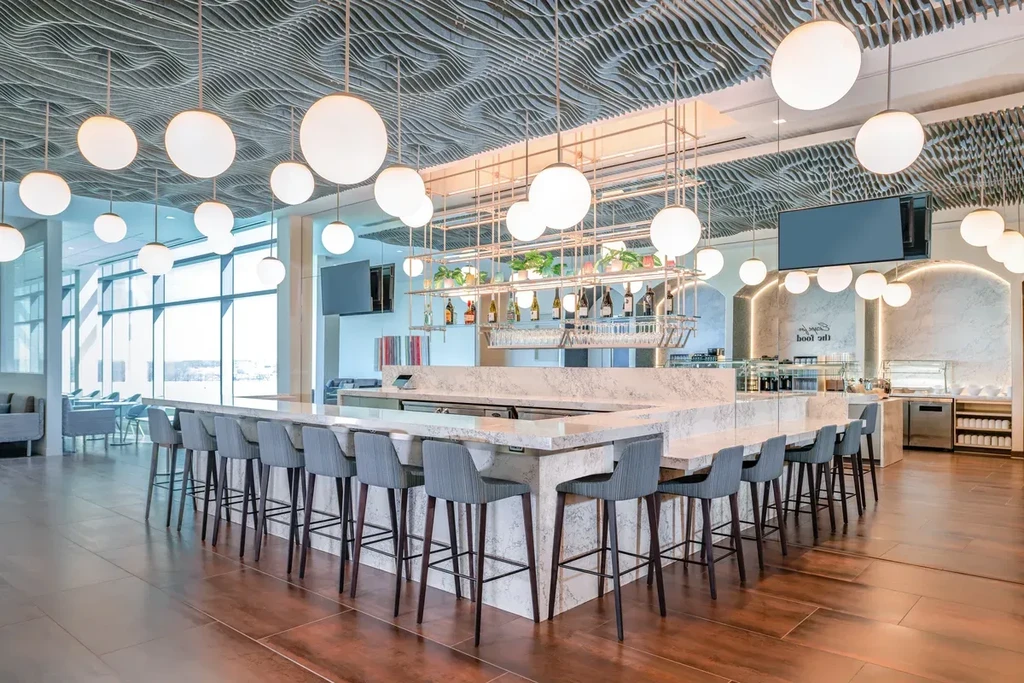 Modern bar with marble counter, globe lights, and dark wood floors.
