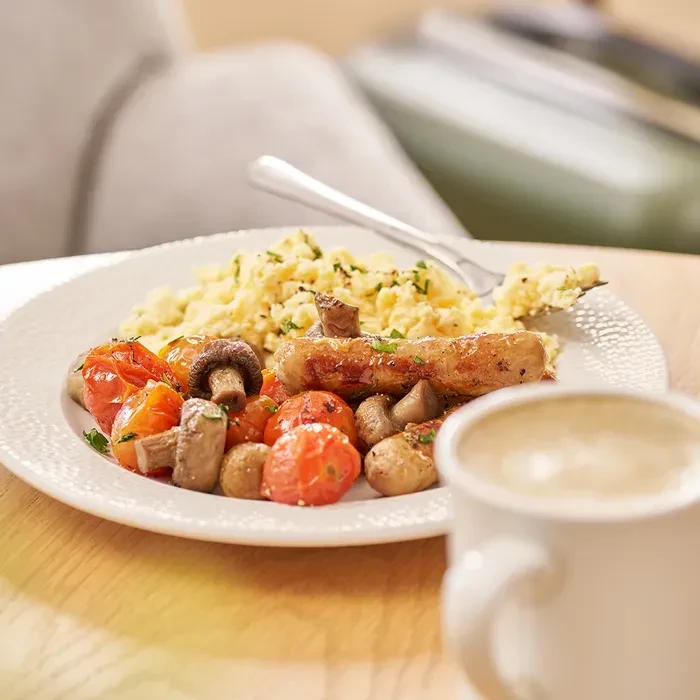 A full breakfast with scrambled eggs, sausage, tomatoes, and mushrooms.