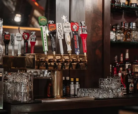 Multiple branded beer tap handles lined up at a bar counter.
