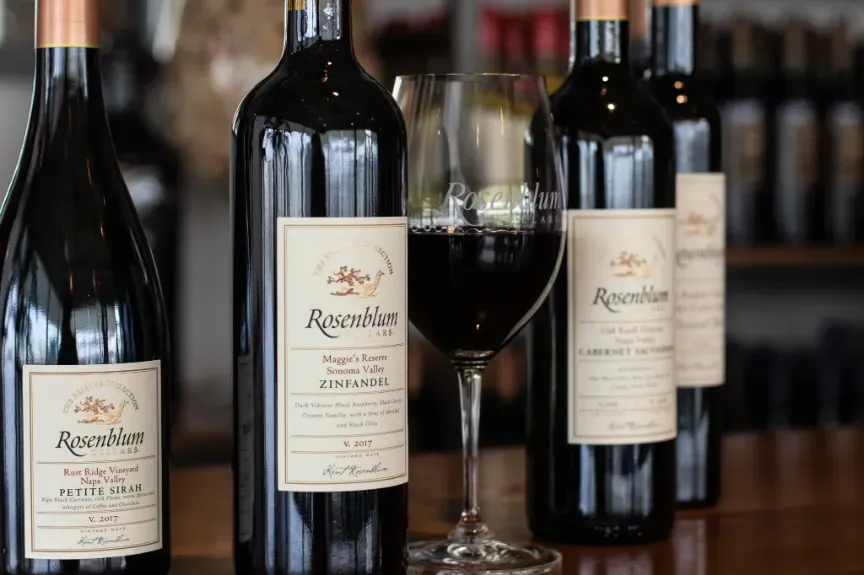 Several Rosenblum red wine bottles and a glass of red wine.