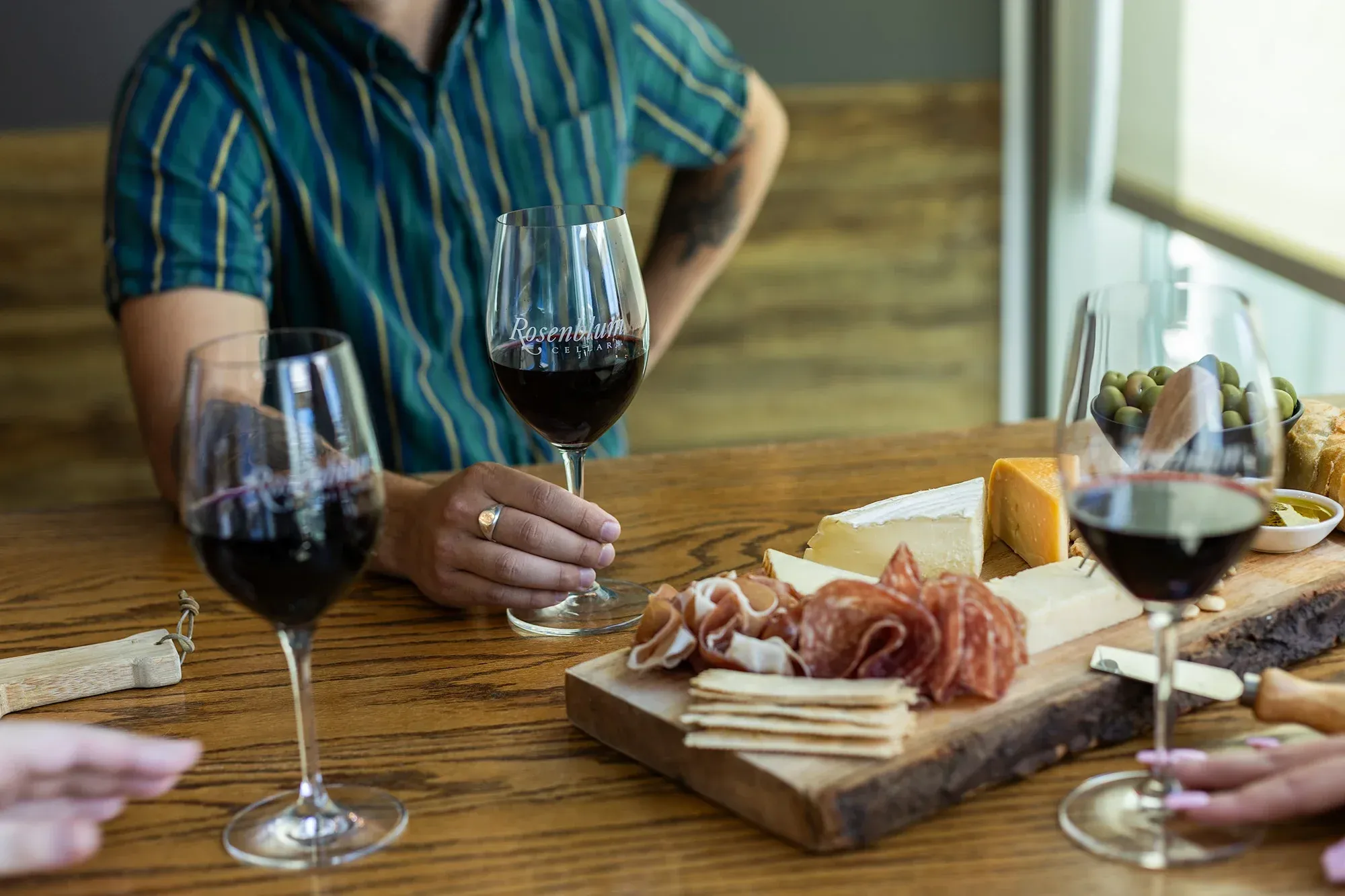 A person holds a glass of red wine at a tasting.