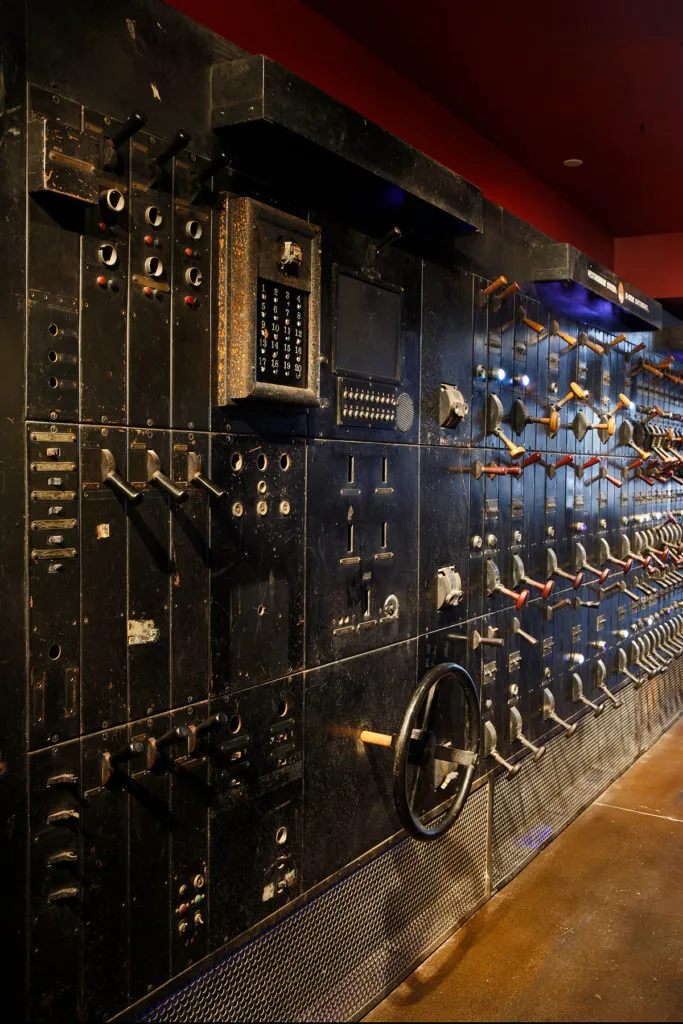 Old industrial control panel with many levers, switches, and a numeric display.